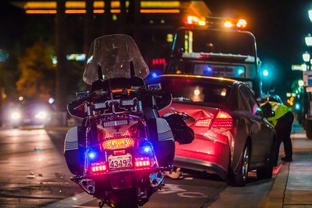 a police motorcycle in front a wrecked car at night